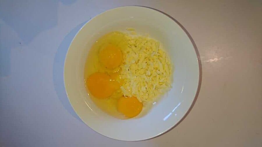 Raw eggs and grated cheese in a bowl