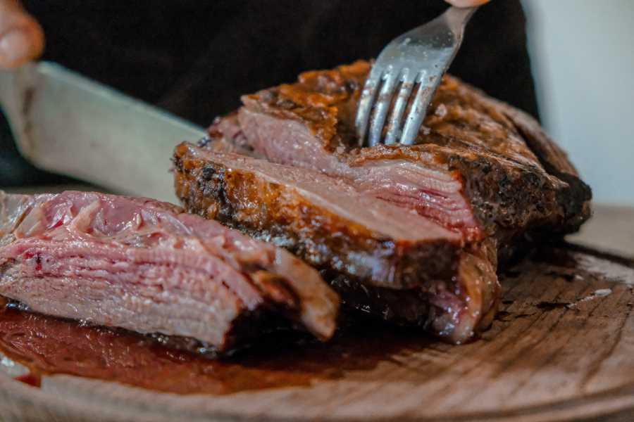 A person slicing meat with a knife and a fork - meat is what you are going to eat a lot on the carnivore diet