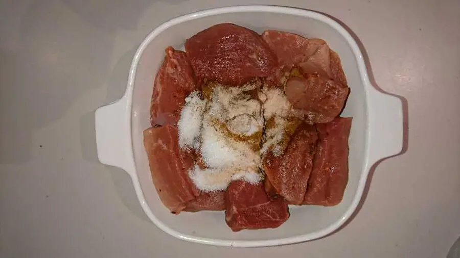 A bowl of raw pork pieces with spices on top