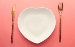 An empty plate and a knife and fork on a pink background