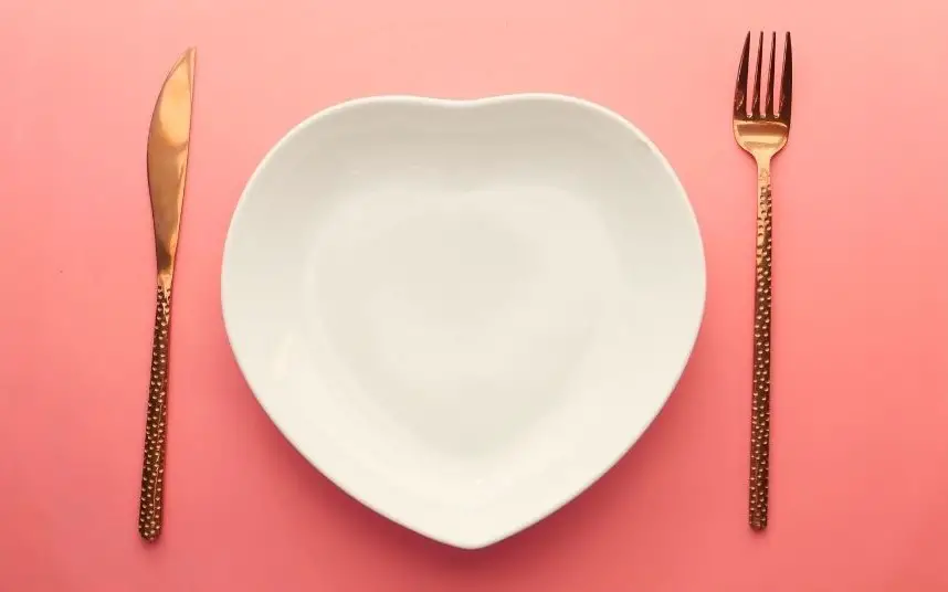 A long water fast on the carnivore diet can have many health benefits – Copy An empty plate and a knife and fork on a pink background