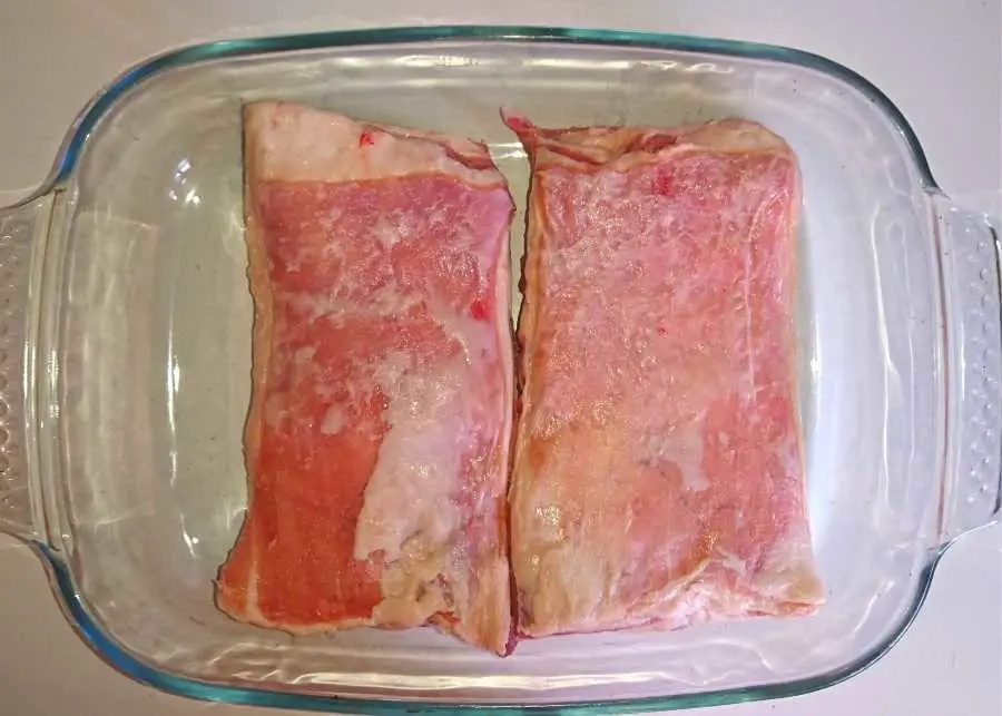 Two raw lamb rib racks in a baking dish