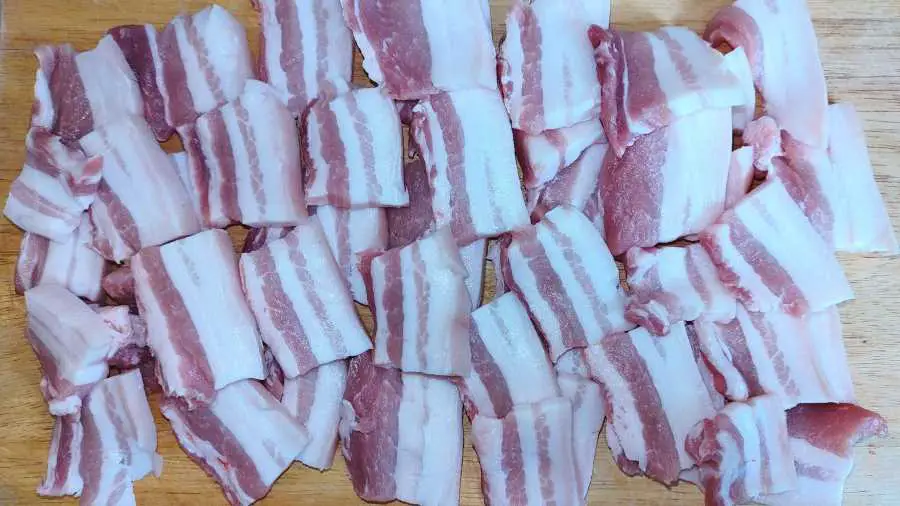 raw slices of pork belly on a wooden board