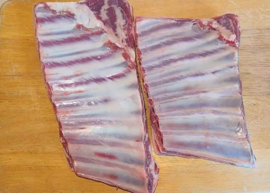 two chunks of lamb ribs on a chopping board