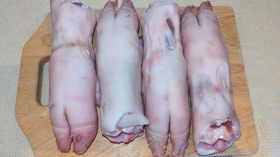 Four pig trotters on a chopping board