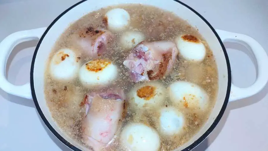 Pig trotter pieces and eggs in a pot ready for braising