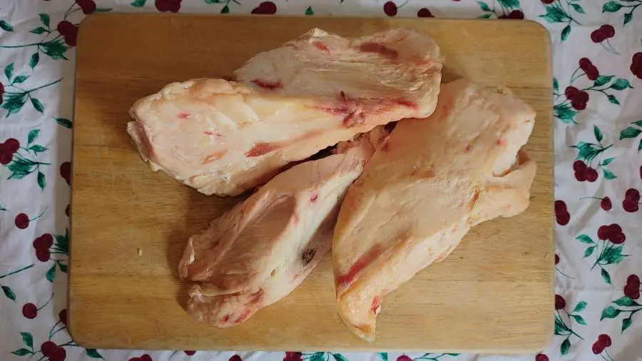 Three large chunks of beef fat on a chopping board